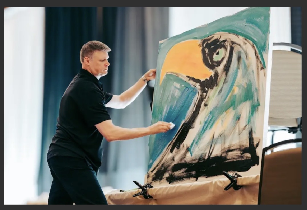 Sam Glenn painting a large eagle during a live presentation