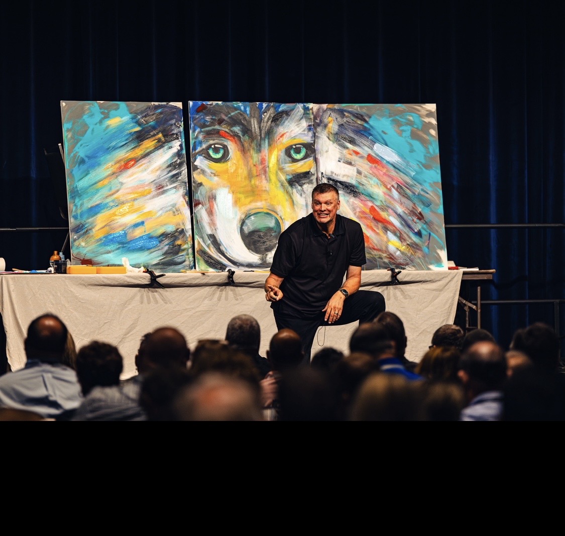 Sam speaking with an audience in front of his completed wolf painting