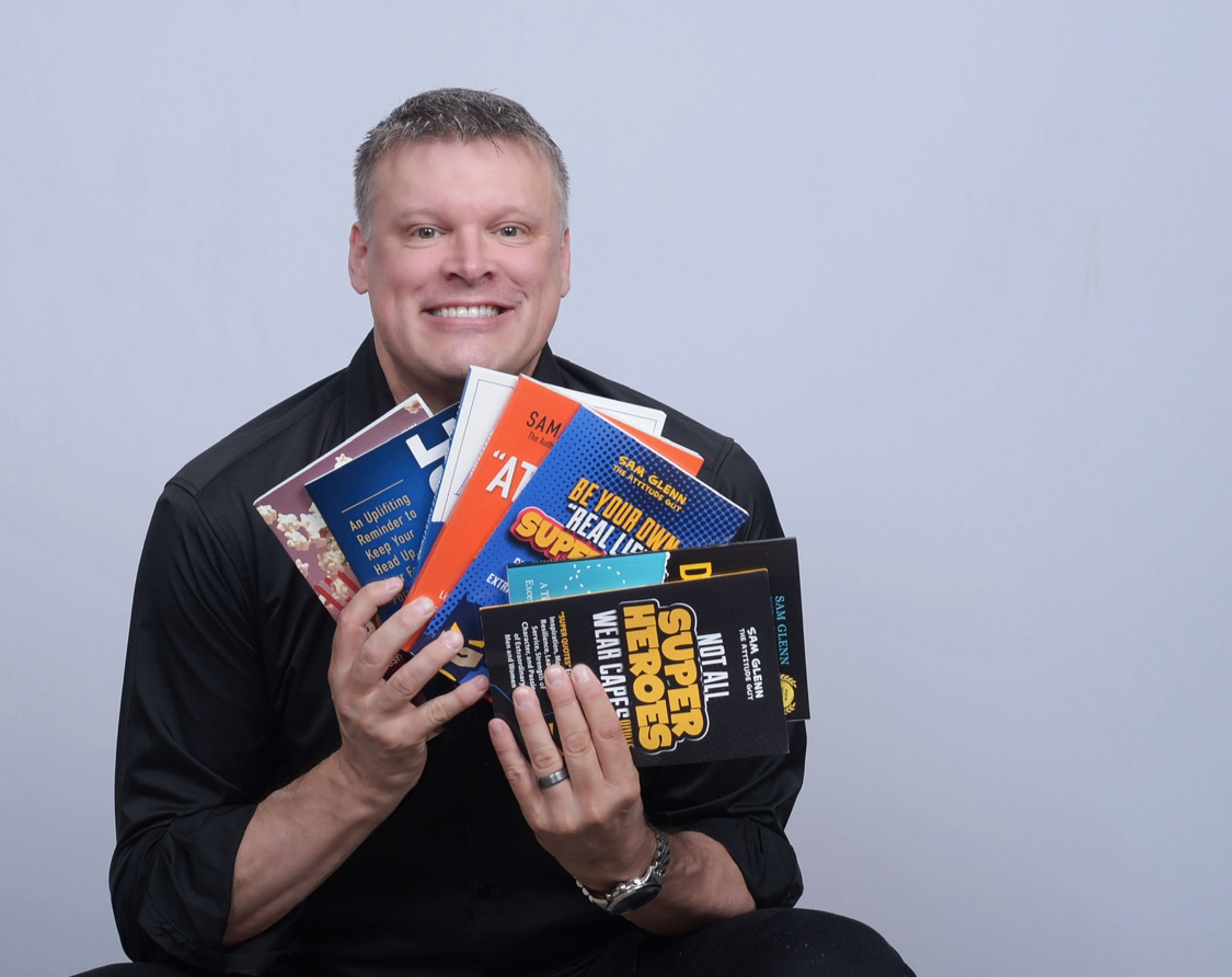 Sam Glenn holding a selection of his books